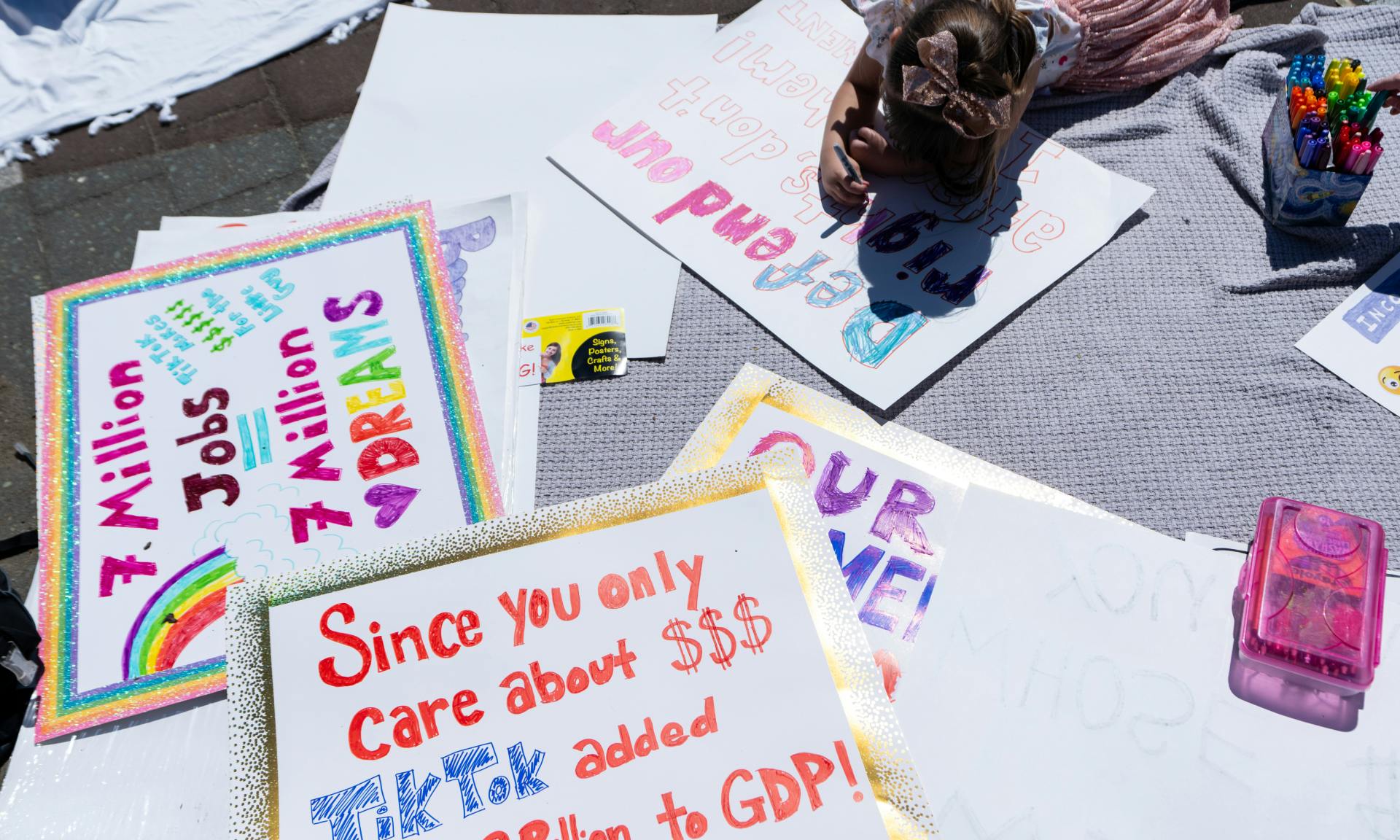 A girl colors posters as a small group of pro-TikTok activists gather on the East Plaza of the U.S. Capitol on Tuesday, April 23, 2024