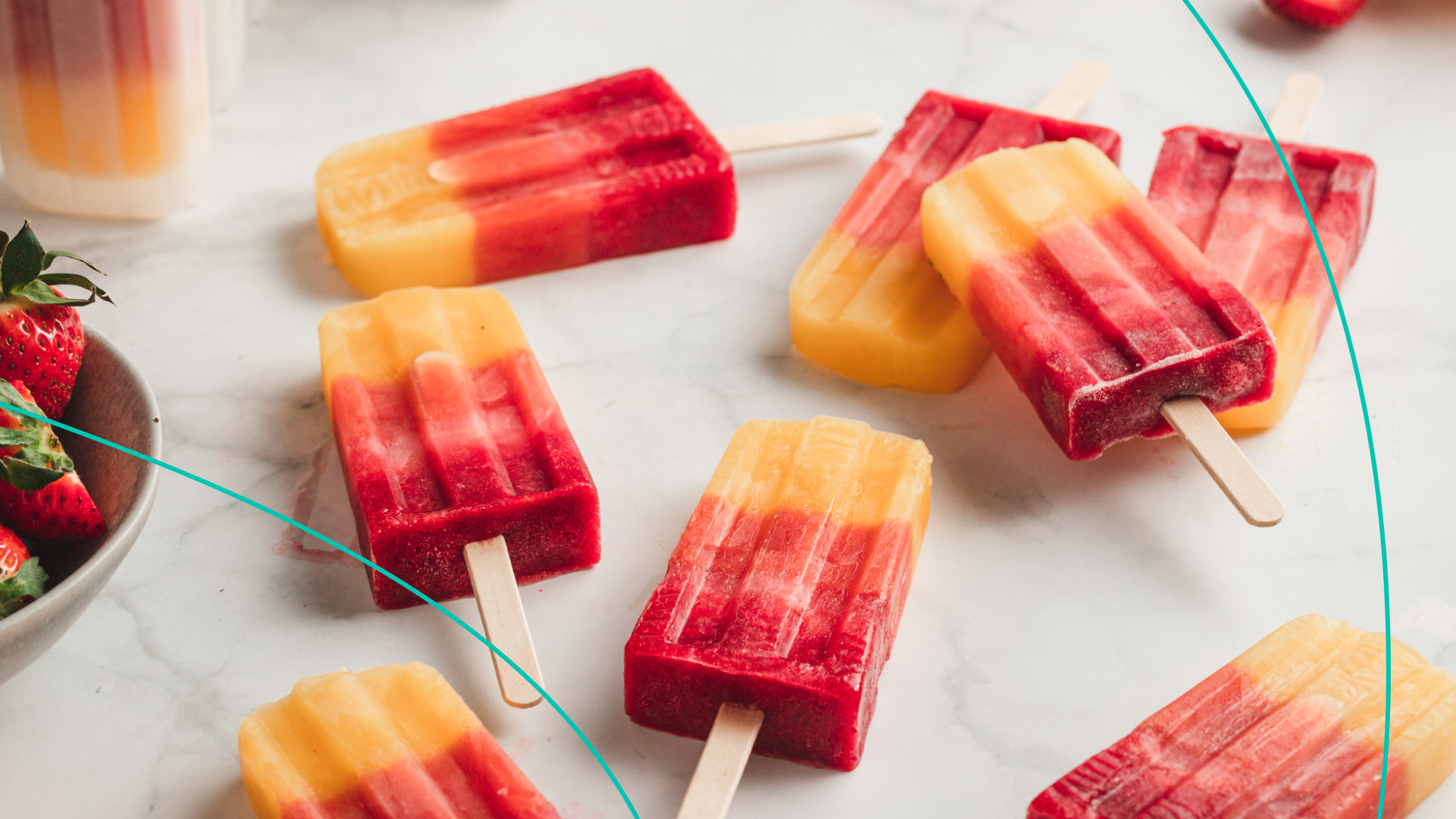 Colorful popsicles next to a bowl of strawberries