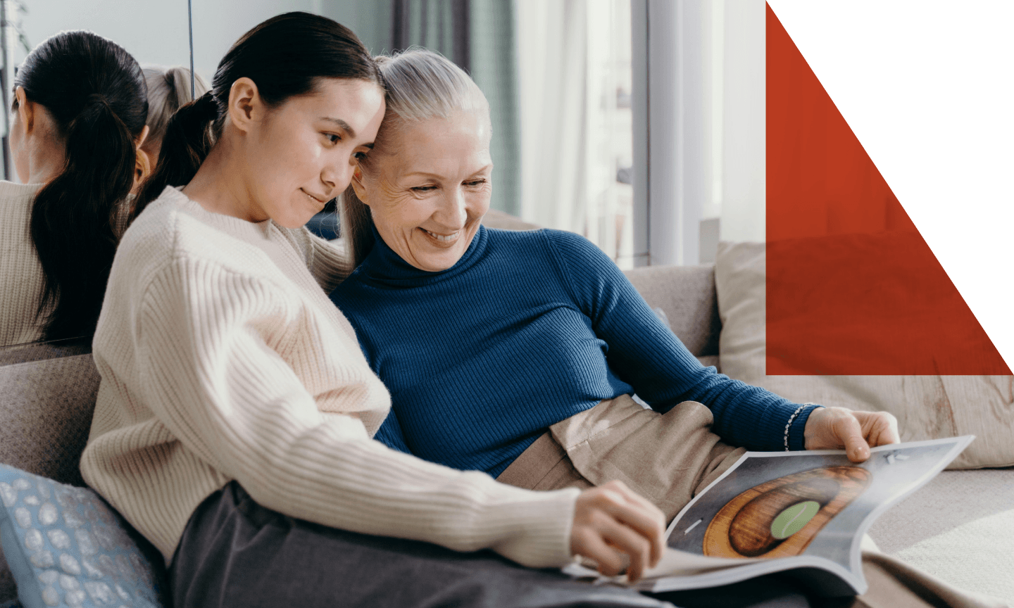 two women on couch looking at magazine together