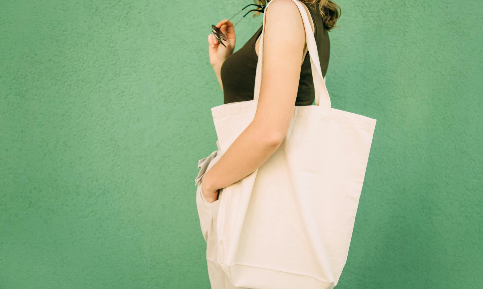 Beautiful blonde girl with eco bag over green background