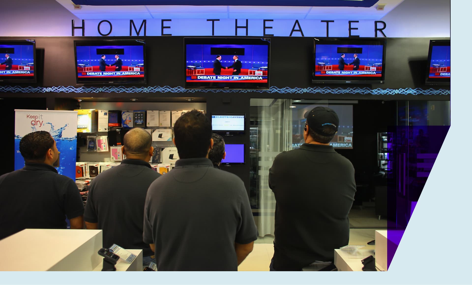 A group of men huddle in front of multiple screens