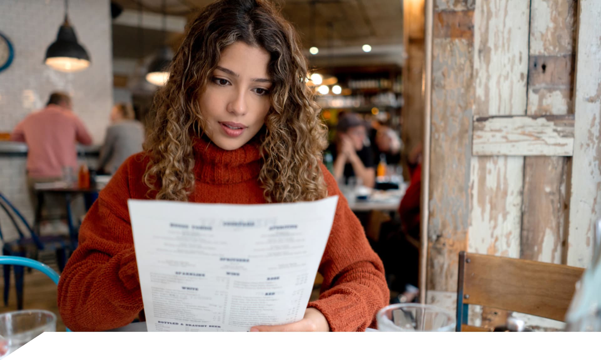 A woman at a restaurant looking at a menu