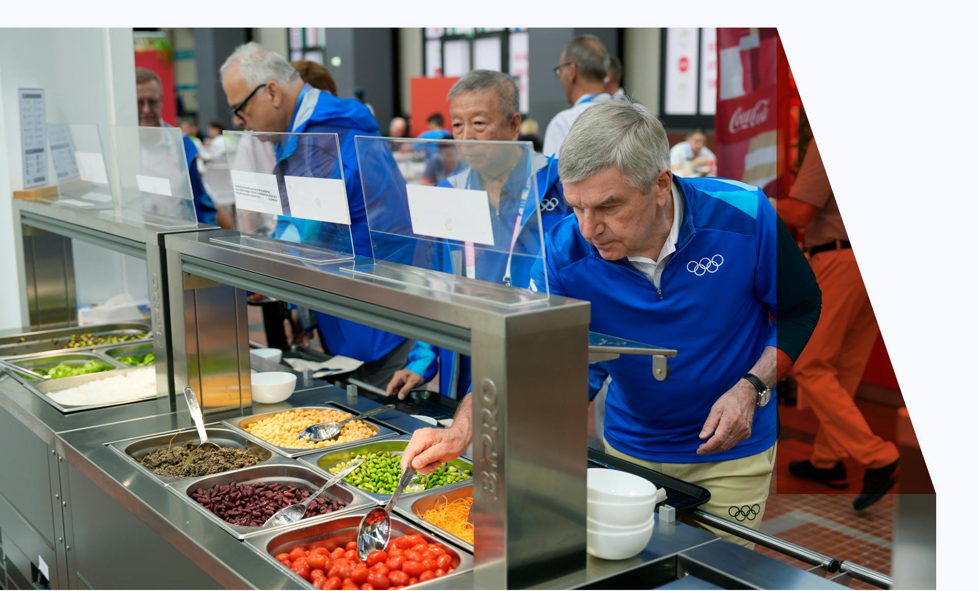 IOC staff trying food from a salad bar while touring the Olympic Village.
