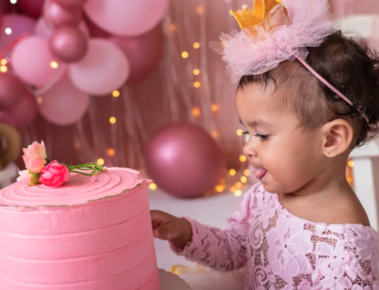 baby girl in pink with pink cake and balloons