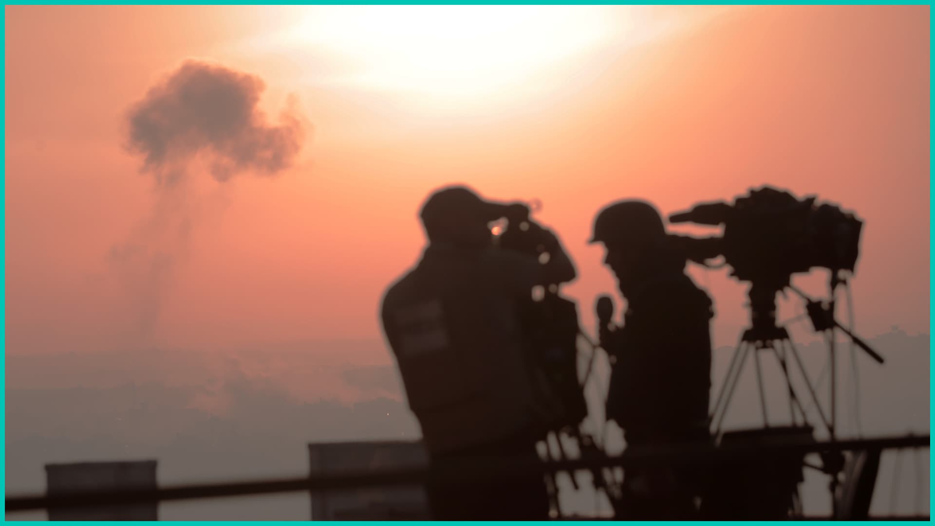 Palestinian journalists are working with an image of an Israeli airstrike in the background, on October 15, 2023. (Photo by Momen Faiz/NurPhoto via Getty Images)