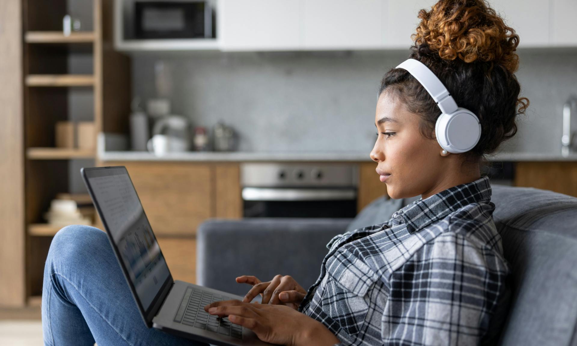 young woman on laptop with big headphones on