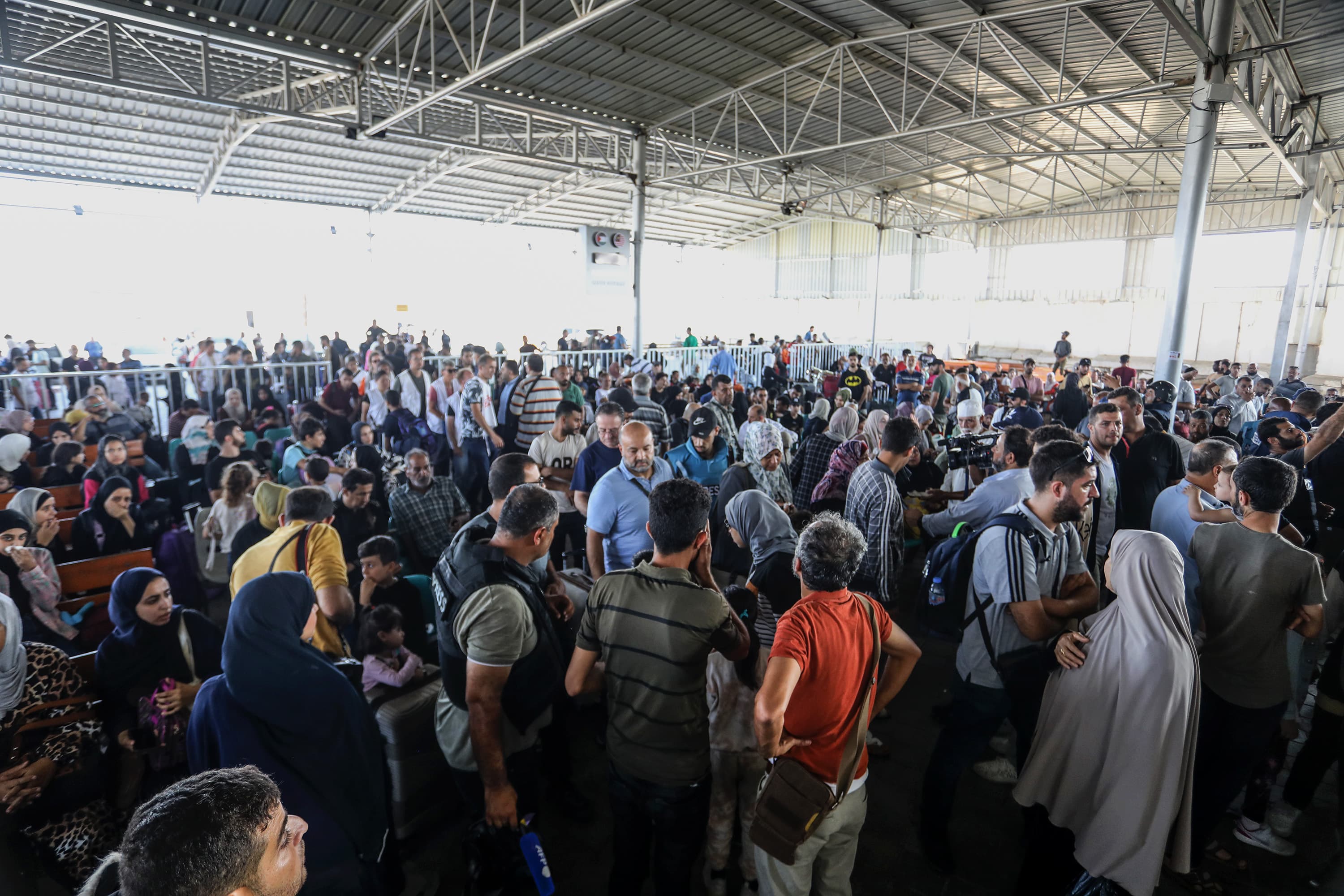 Palestinians with foreign passports at Rafah Border Gate wait to cross into Egypt as the Israeli airstrikes continue