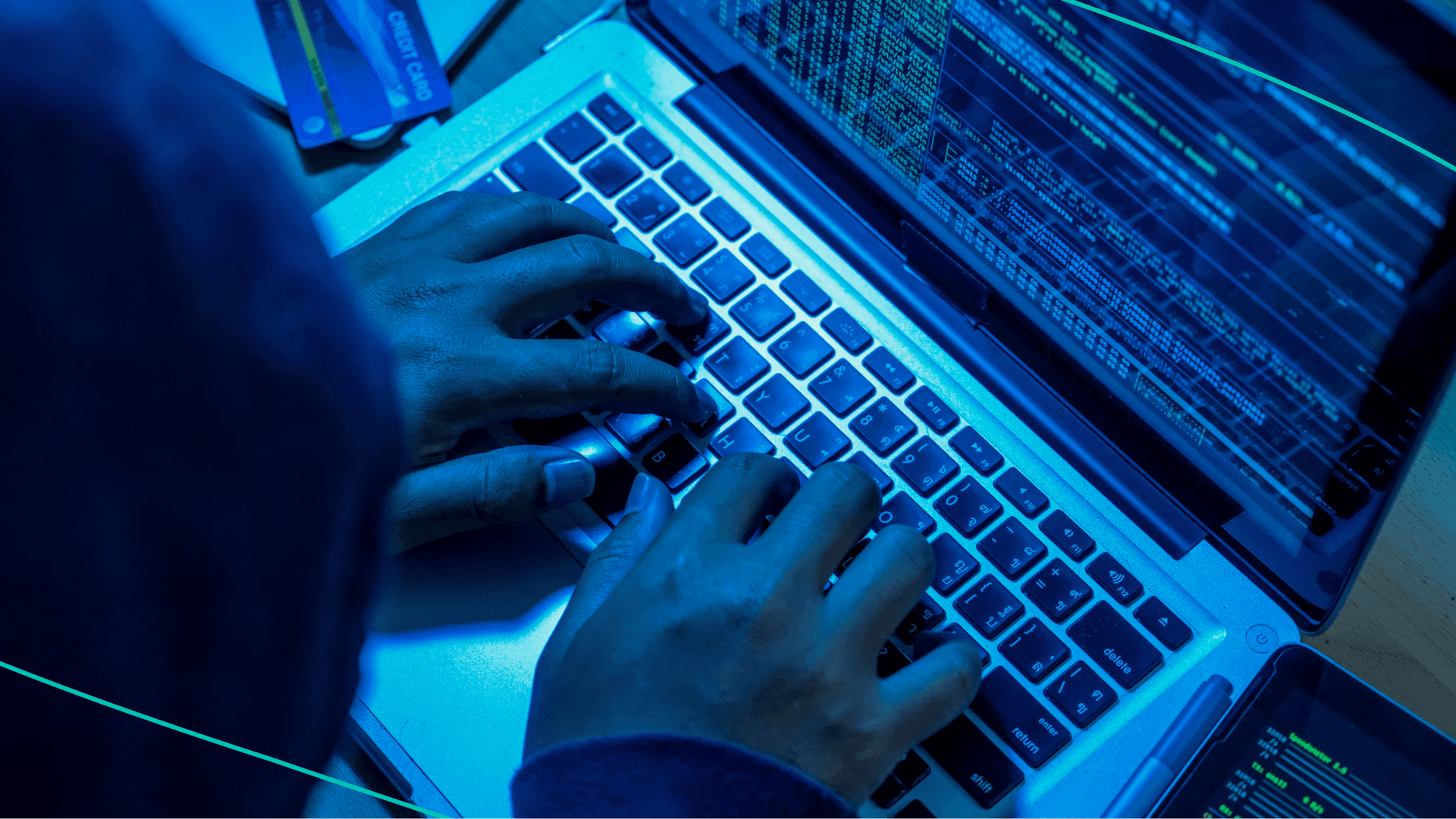 Person in black hood typing on laptop