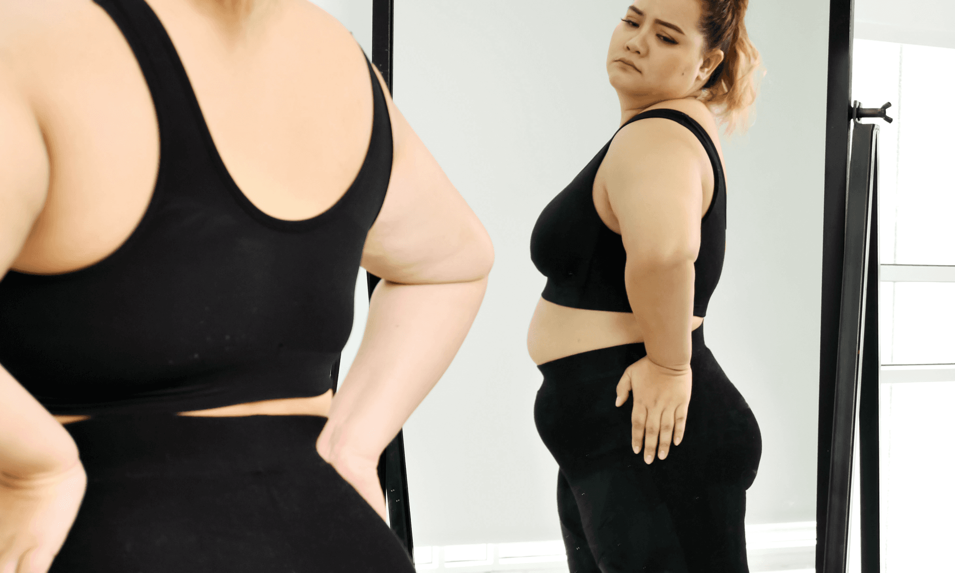 Woman looking at stomach in mirror
