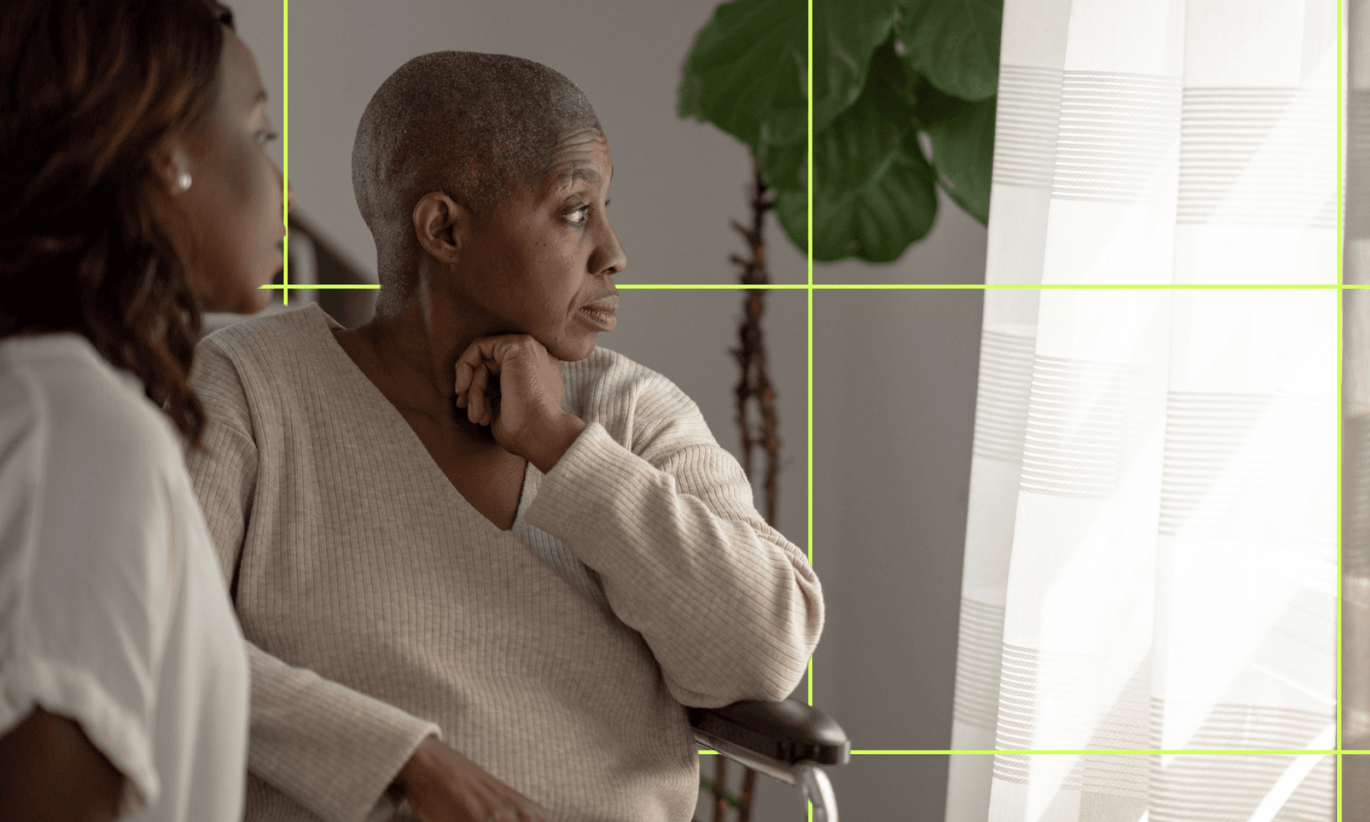 A young Black woman and an older Black woman sit on a bench in a park together