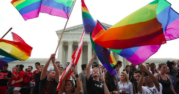 People waving Pride flags in front of the Supreme Court Building